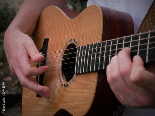Acoustic guitar playing musician close up of guitar, strings, fretboard and hands