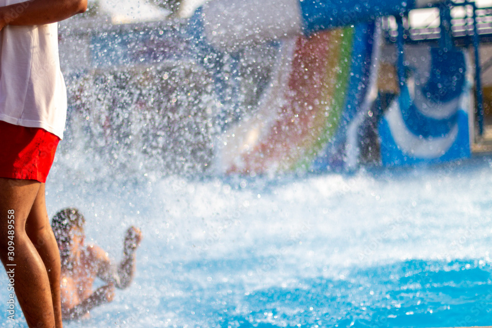 A man passes by water glides in summer outdoor water park.