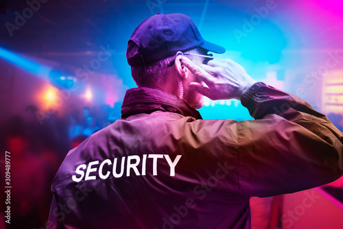 Security Guard Listening To Earpiece Against Building