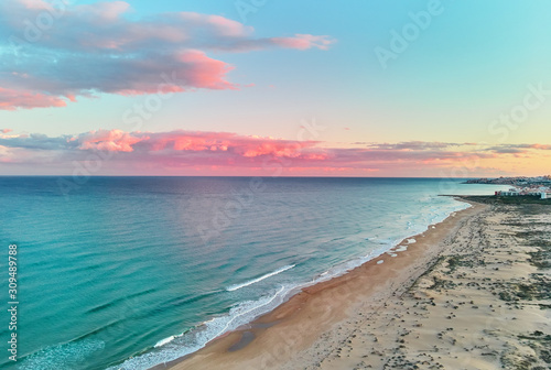 Picturesque scenery aerial drone view landscape, calm blue Mediterranean Sea colourful fluffy glowing pink clouds at sunset evening sky, sandy coastline. La Mata, Torrevieja, Costa Blanca, Spain