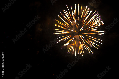 White and yellow fireworks in the shape sphere on the right side on a black background.