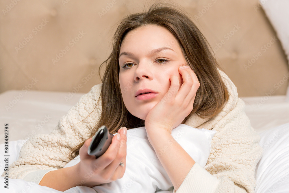 Young woman on the bed holding remote control Young woman on the bed holding remote control