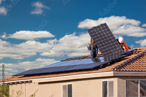 Workers Installing Solar Panels on House Roof photo