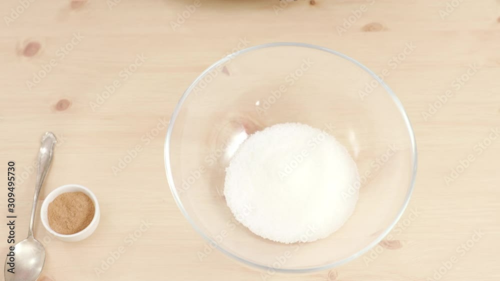 Woman adding sugar in glass bowl shot from above Woman adding sugar in glass bowl shot from above
