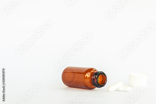 white pills spilling out brown glass supplement medicine isolated on white background 