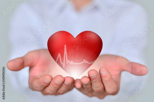 The close-up businessman holds a 3D red heart, a concept of health, medicine, people and heart disease.