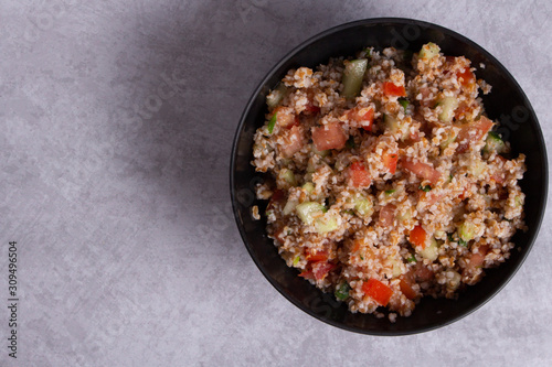 Traditional Arabic Salad Tabbouleh with couscous, vegetables and greens