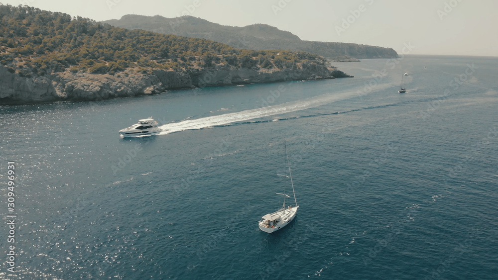 Aerial View of yacht near rocky island of Mallorca. Drone footage of yachting around Balearic islands in the mediterranean sea 