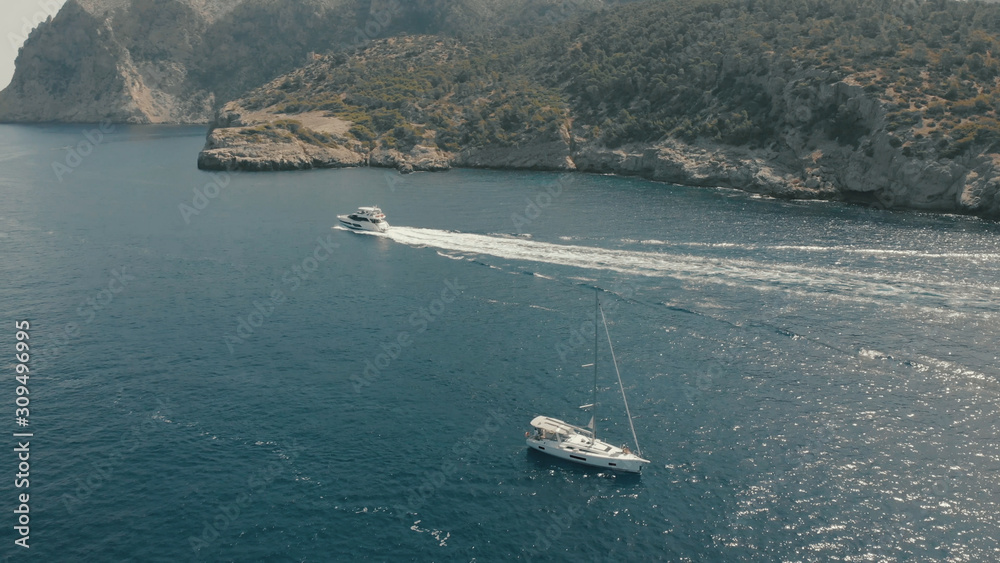 Aerial View of yacht near rocky island of Mallorca. Drone footage of yachting around Balearic islands in the mediterranean sea 