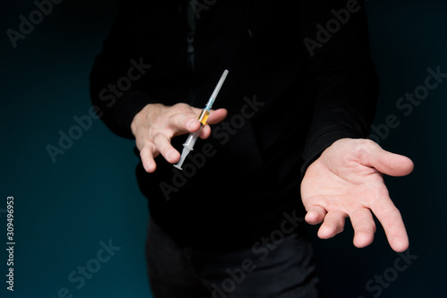 man shows a syringe with a drug and holds out an empty palm  waiting for payment