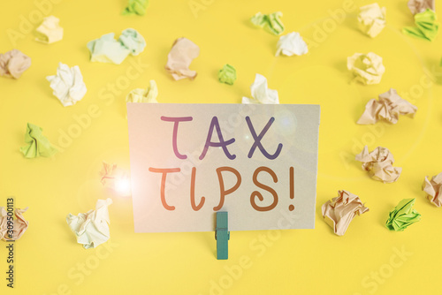 Conceptual hand writing showing Tax Tips. Concept meaning compulsory contribution to state revenue levied by government Colored crumpled paper empty reminder white floor clothespin © Artur