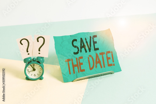 Conceptual hand writing showing Save The Date. Concept meaning remember not schedule anything else on this day Alarm clock beside a Paper sheet placed on pastel backdrop