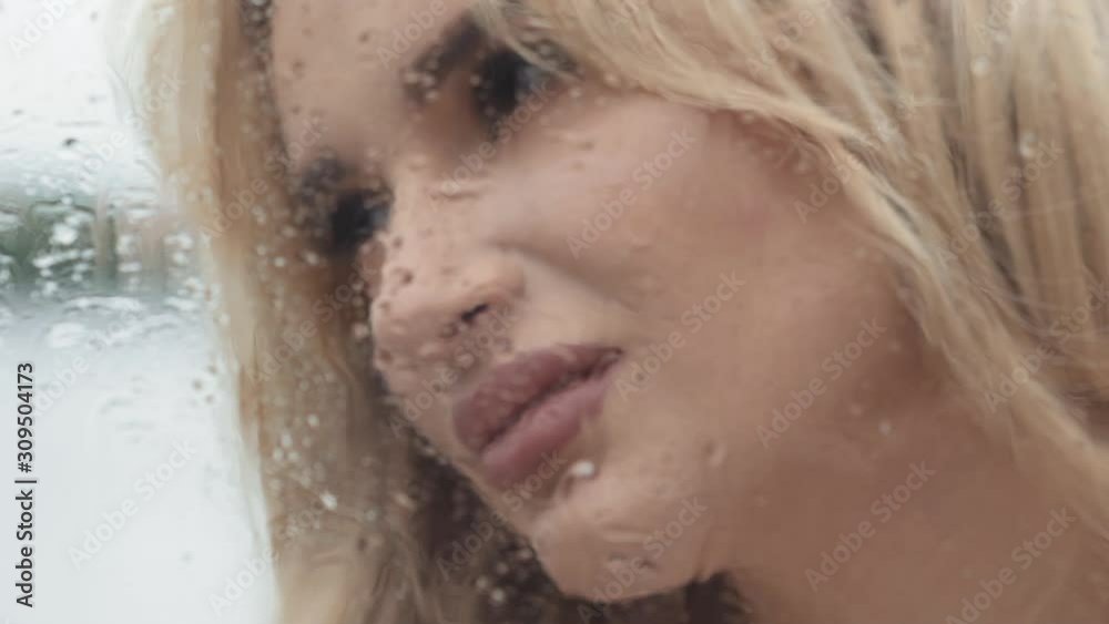 Passionate portrait of blonde touches wet from rain window Passionate portrait of blonde touches wet from rain window