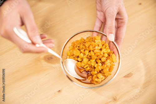 Close up of woman's hands stirring raisins and rum in glass bowl
