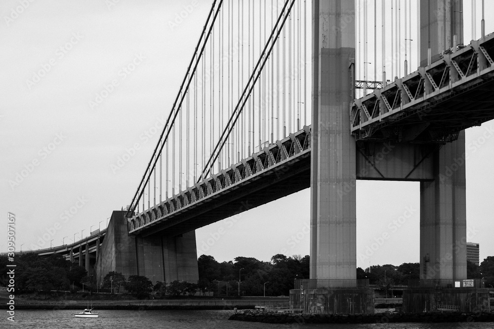Fototapeta Greyscale of the Manhattan bridge in New York surrounded by water and greenery