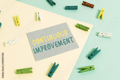 Conceptual hand writing showing Continuous Improvement. Concept meaning ongoing effort to improve products or processes Colored clothespin paper reminder with yellowblue background