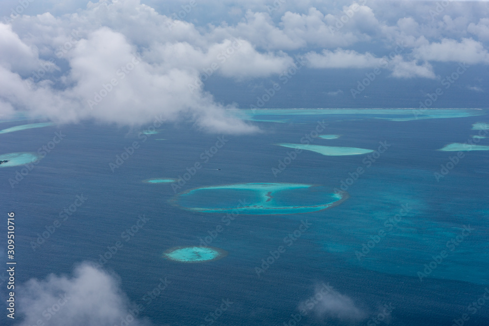 Islands view from the window of the plane. Beautiful atolls and bright colors of the sea