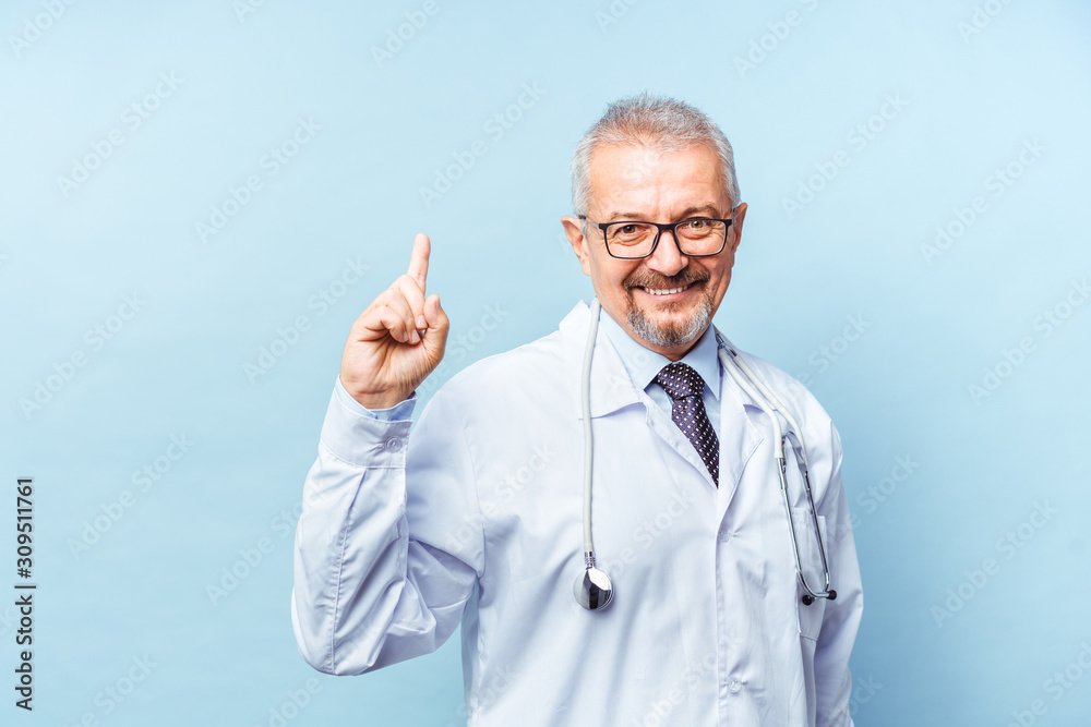 Smiling medical senior doctor with a stethoscope. On a blue background. Medic shows thumb raised up. The concept of humanity's victory over disease