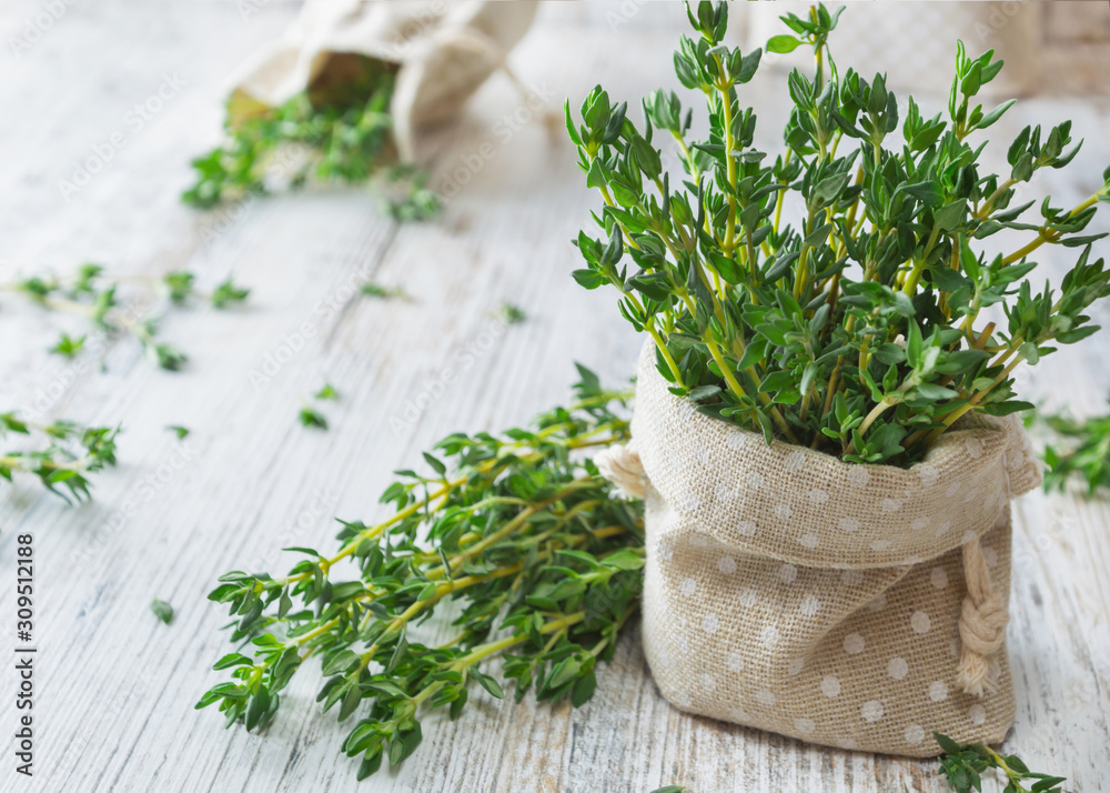 Fresh green thyme in decorative linen bag on an old wooden table. - obrazy, fototapety, plakaty 