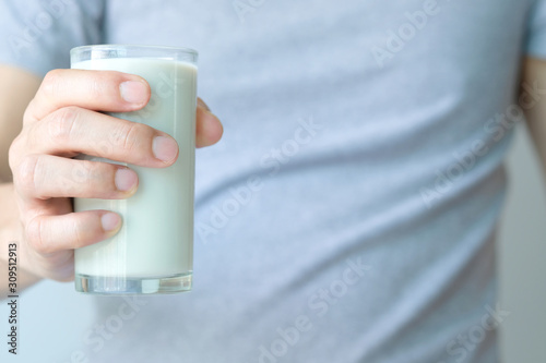 In the morning, a man's hand held a glass of soy milk to drink.