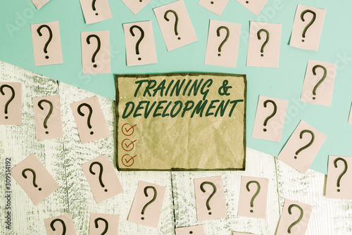 Writing note showing Training And Development. Business concept for learn specific knowledge to improve perforanalysisce Scribbled and crumbling papers with thick cardboard above wooden table