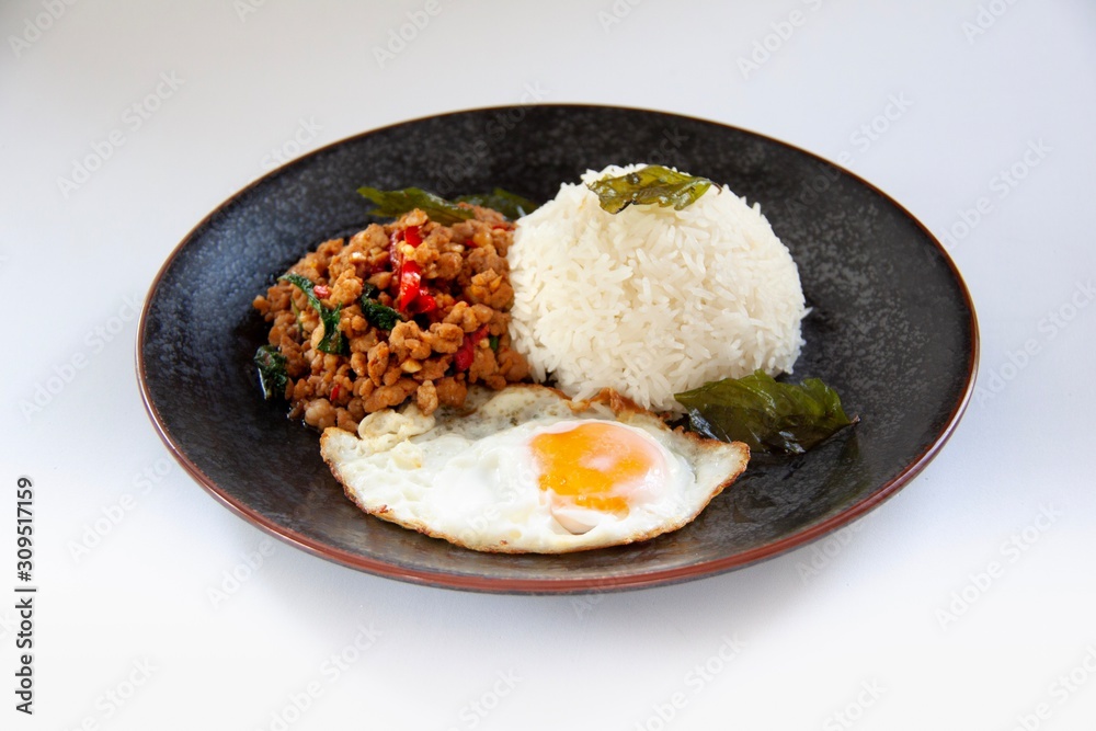 Favorites Thai food, Jasmine rice with organics stir-fried pork holy basils and fried egg served in black dish on white background, Isolated image.