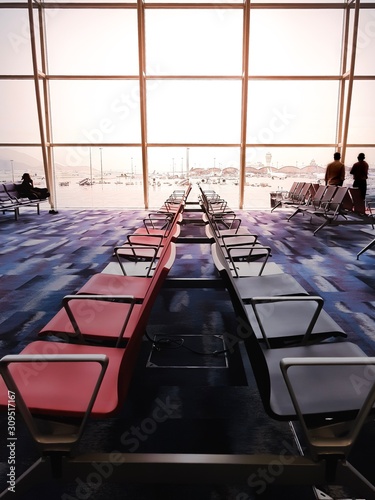 Empty airport waiting area with chairs and tables near a window overlooking the airplane on the runway
