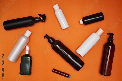 White and black plastic bottles of different sizes on an orange background. Ecology concept, cosmetics