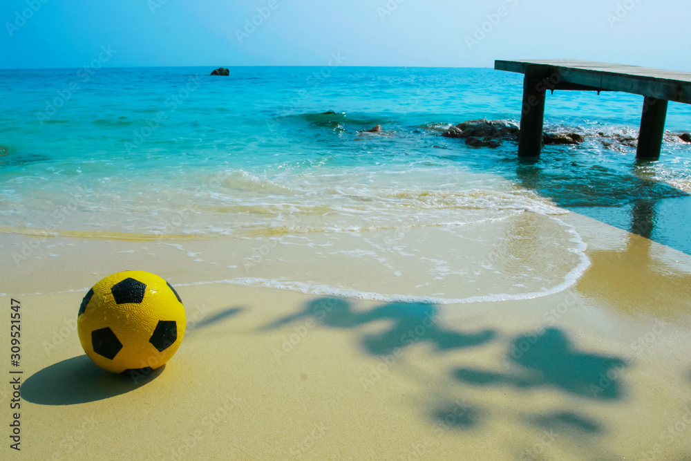 Naklejka premium yellow ball on beach with blue sea background