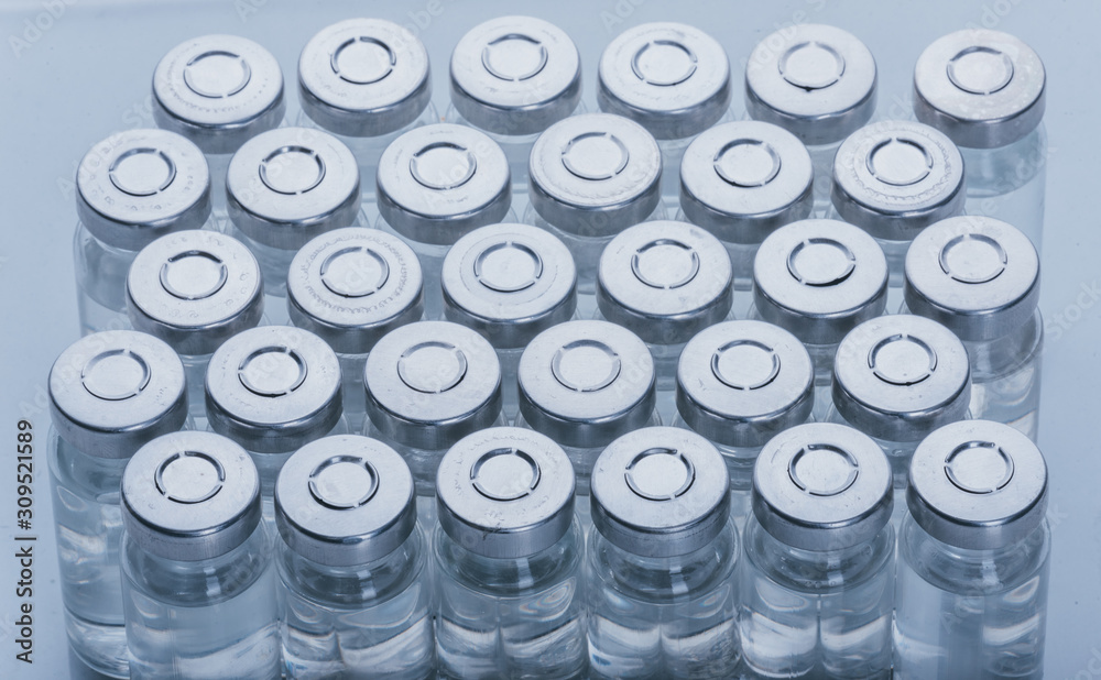 Glass medical ampoule vial for injection. Medicine is dry white drug penicillin powder or liquid with of aqueous solution in ampulla. Close up. Bottles ampule with aluminum cap on backgrounds gray. Glass medical ampoule vial for injection. Medicine is dry white drug penicillin powder or liquid with of aqueous solution in ampulla. Close up. Bottles ampule with aluminum cap on backgrounds gray.