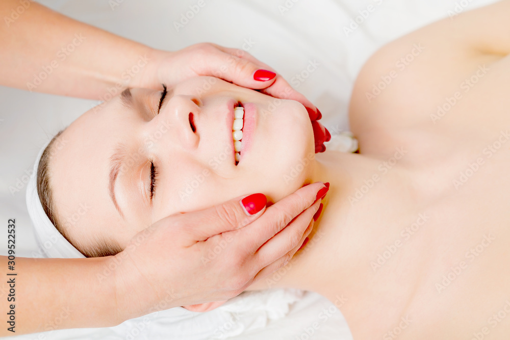 Beautiful young woman receiving facial massage with closed eyes in a spa salon Beautiful young woman receiving facial massage with closed eyes in a spa salon