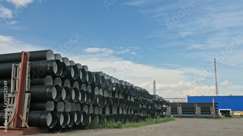 Warehouse of finished plastic pipes industrial outdoors storage site. Manufacture of plastic water pipes factory. Process of making plastic tubes on the machine tool with the use of water and air