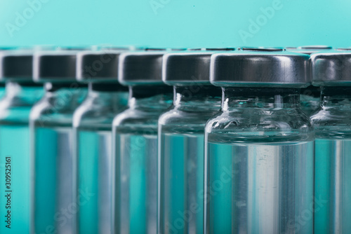 Glass medical ampoule vial for injection. Medicine is liquid sodium chloride with of aqueous solution in ampulla. Close up. Bottles ampule multicolor on background color and water. Human plasma.