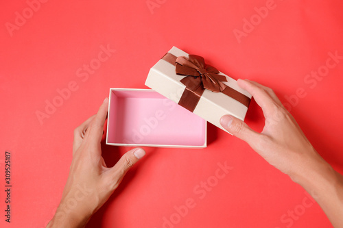 Use a hand to open the Gift box on a red background.