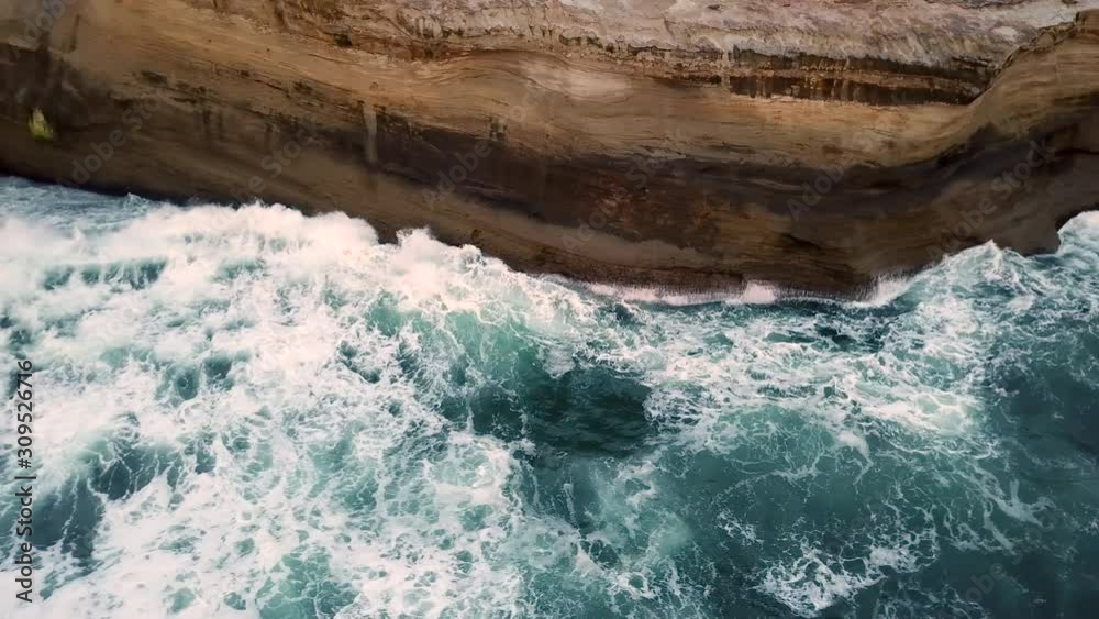 Ocean waves crashing into sandstone cliffs at Cape Kiwanda near Oregon coast, aerial dolly shot Ocean waves crashing into sandstone cliffs at Cape Kiwanda near Oregon coast, aerial dolly shot