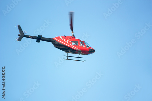 Red passenger helicopter on blue sky background
