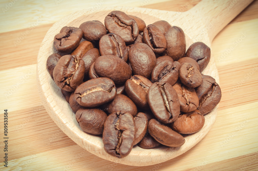 Heap of coffee grains with spoon on wooden board Heap of coffee grains with spoon on wooden board