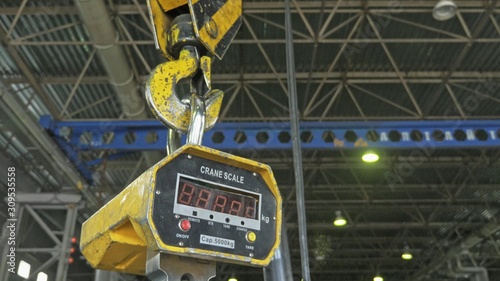 Industrial type 5000 kg digital weight scale hanging on hook of the crane, with clipping path. Manufacture of plastic water pipes factory.