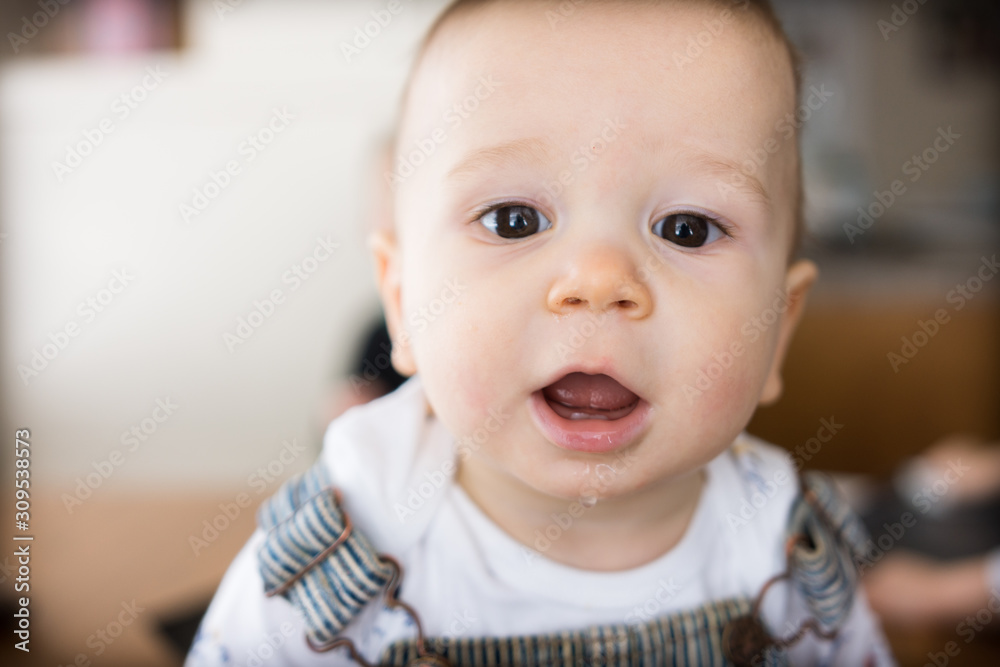 Young cute infant boy smiles in casual home setting