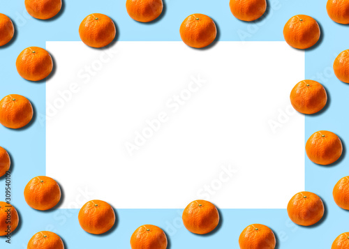 Citrus concept with blank space. Orange mandarins repeats on a soft blue background. 