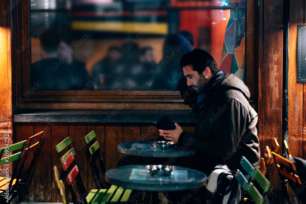 one man sitting at a cafe terrace using mobile phone