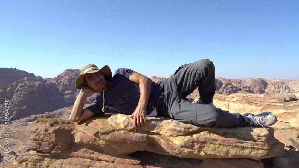 latin man rich out the peak of mountain and having a rest, happy adventure, man tourist trekking outdoor, travel concept