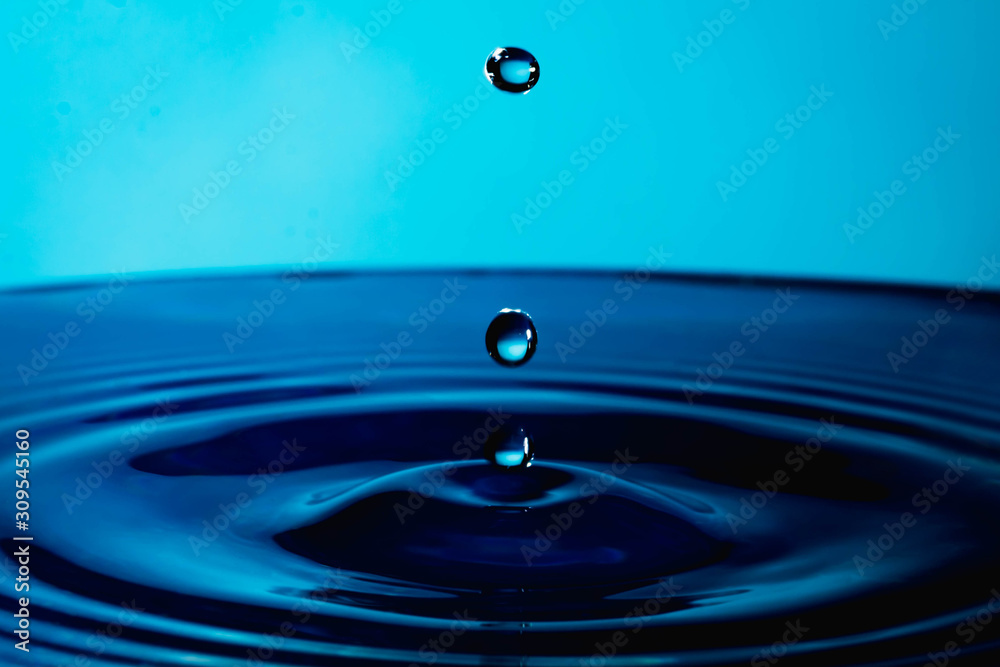 Water drop splash in a glass cup blue colored Water drop splash in a glass cup blue colored