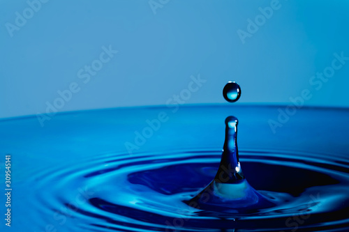 Water drop splash in a glass cup blue colored