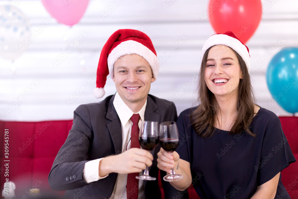 Couples wear red Santa hats holding a glass of wine to celebrate the New Year. Couples wear red Santa hats holding a glass of wine to celebrate the New Year.