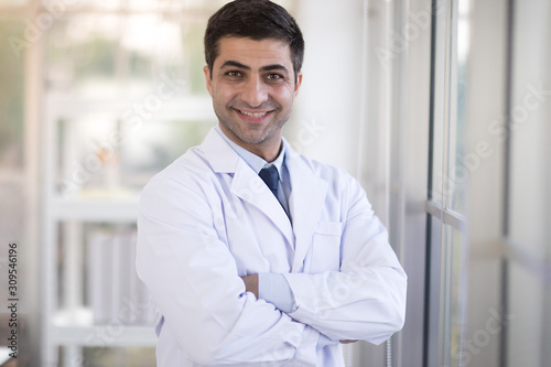 Male doctor wearing a white coat And was smiling at the window, looking at the camera