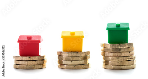 Photos Three houses on piles of new pond coins on a white background