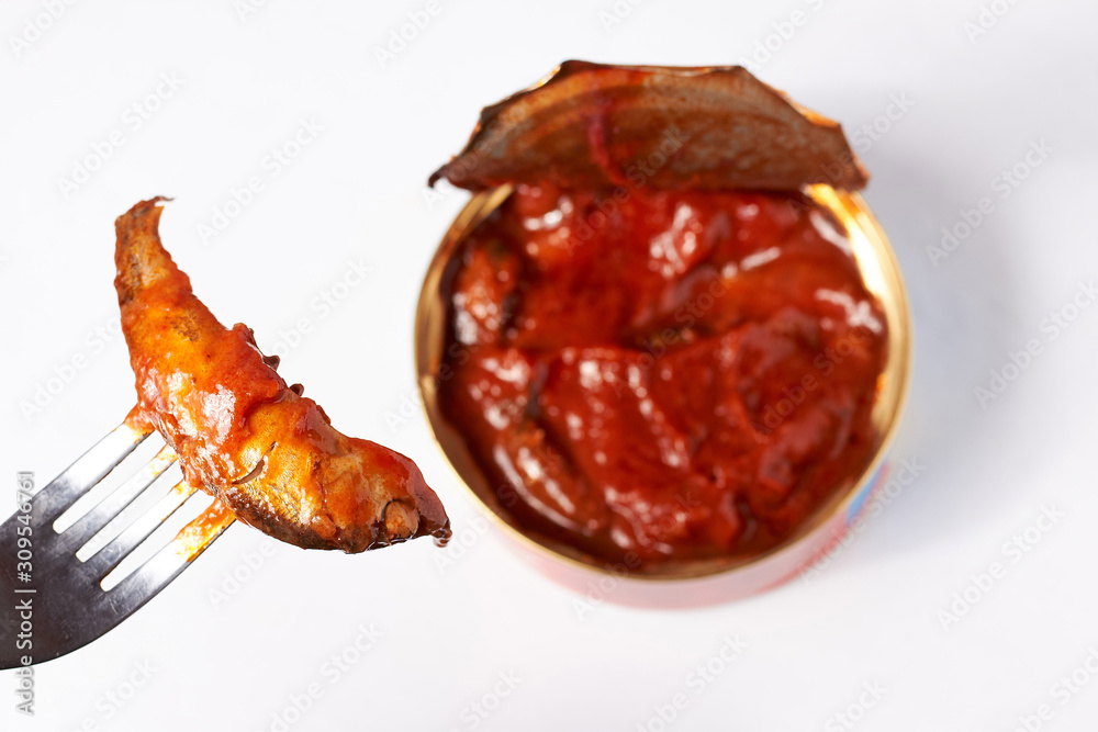 Photo on a whitish background canned seafood in an open jar, fish on a fork.