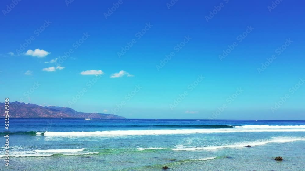 Colorful seascape with white waves foaming over calm turquoise lagoon under bright blue sky background in Indonesia Colorful seascape with white waves foaming over calm turquoise lagoon under bright blue sky background in Indonesia