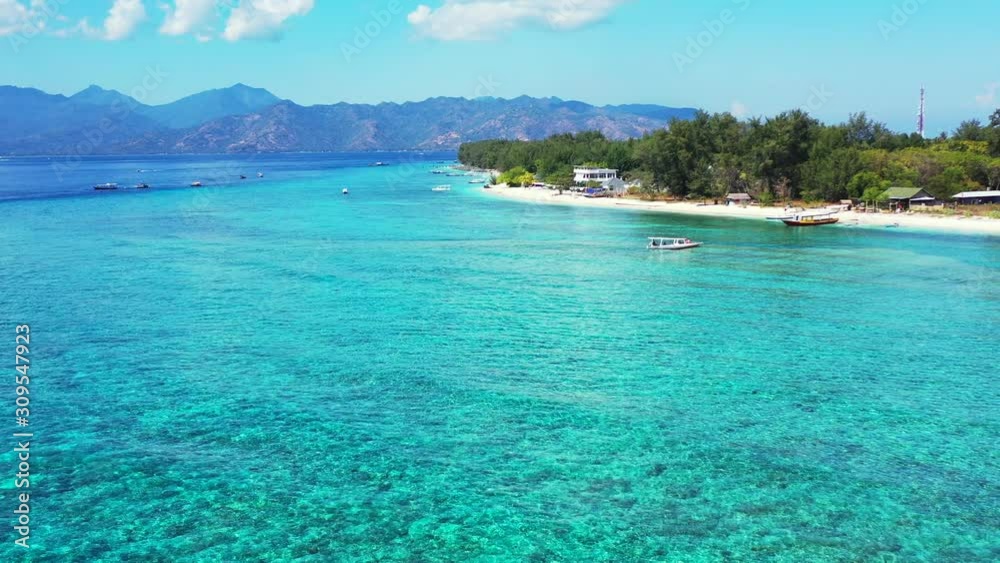 Calm clear water of turquoise lagoon over rocky sea bottom, boats floating near shore of tropical island on a bright sky background Calm clear water of turquoise lagoon over rocky sea bottom, boats floating near shore of tropical island on a bright sky background
